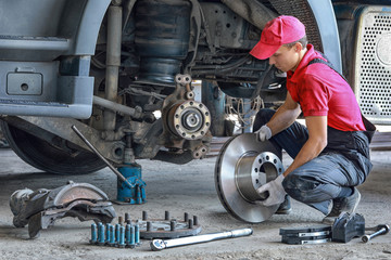 A mechanic repairs a truck. Replace brake disc and pads	