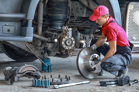 A mechanic repairs a truck. Replace brake disc and pads	