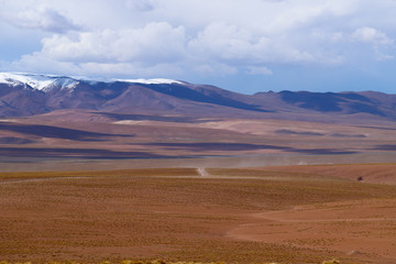 Fototapeta na wymiar Landscape of the Bolivian highlands. Desert landscape of the Andean plateau of Bolivia with the peaks of the snow-capped volcanoes of the Andes