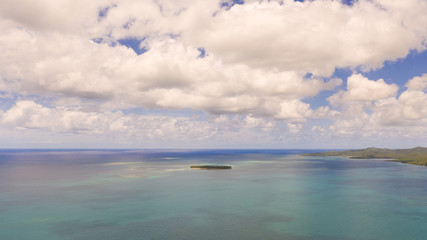 Seascape, coast of the island of Siargao, Philippines. Blue sea with waves and sky with big clouds, top view.