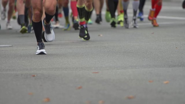 Urban Marathon runners on the street. Slow motion close-up runners legs