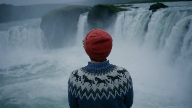 Close up portrait of man in red beanie hat and blue wool traditional scandinavian sweater sit in front of epic wonderful. Travelling wanderlust experience for travel blogger