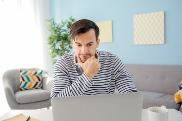 Thoughtful man working on laptop at home
