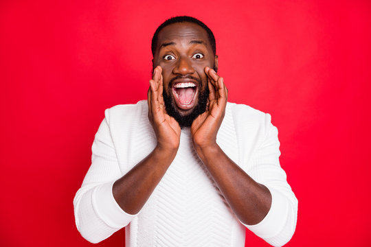 Hey listen new promo. Portrait of crazy funky african man hold hand near mouth shout ads share confidential information wear style white sweater isolated over red color background