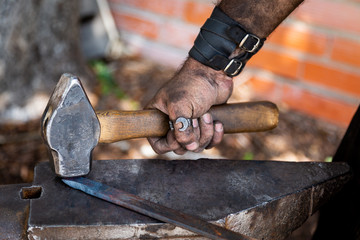 Blacksmith working on metal on anvil at forge detail shot