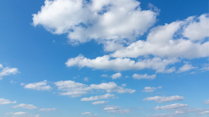 Fluffy white cumulus clouds in the blue sky on a sunny day