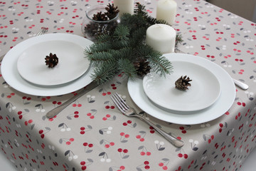 white plates on a table with a Christmas table setting and a tablecloth with a New Year's pattern.