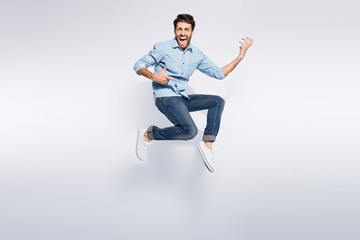 Full length photo of wild multiethnic guy jumping high at hard rock concert playing imagine electric guitar wear casual denim clothes isolated white color background