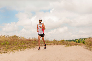 Man running outdoors with a beard in a sports uniform in nature, day, open air
