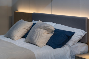 Modern white, blue, brown fabric pillows with brown fabric headboard on the bed interior decoration