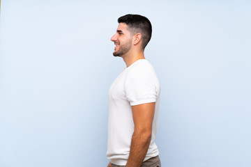 Caucasian handsome man over isolated blue background in lateral position