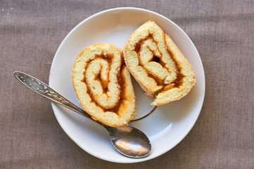 Slices of biscuit roll with apricot jam on a white plate