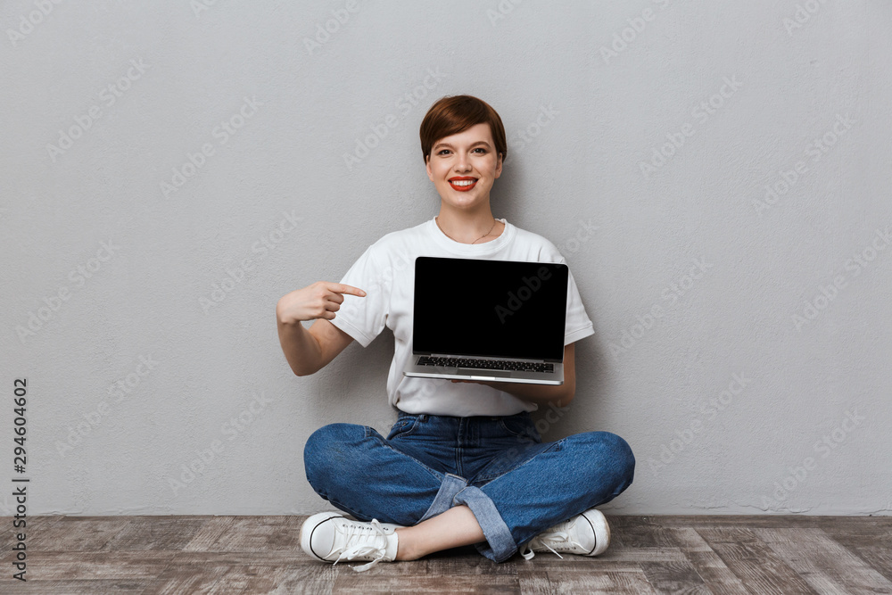 Sticker Image of smiling woman showing laptop screen while sitting on floor