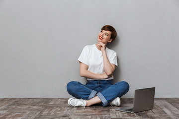 Image of beautiful young woman sitting on floor with laptop computer