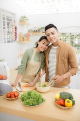 Smiling young Asian couple cooking food in the kitchen