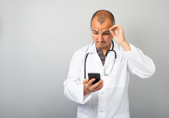 Male doctor is typing a text message on a mobile phone