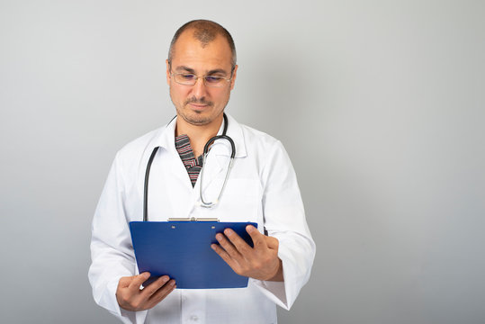 male doctor with a stethoscope around his neck holding documents in his hand