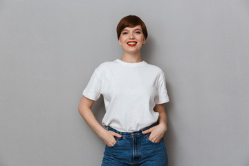 Image of pretty brunette woman wearing casual t-shirt smiling at camera - obrazy, fototapety, plakaty