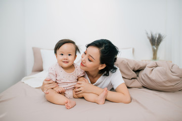 Beatuful mother playing with daughter. Little girl have fun at home.