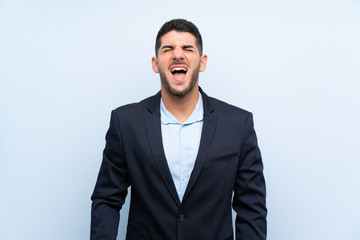 Handsome man over isolated blue background shouting to the front with mouth wide open
