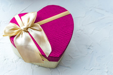 Gift in a box in the shape of a pink heart with a bow on a white background. Romantic gift concept. Valentine's Day