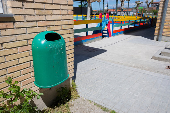 Papelera, valla pintada de colores y columpios en el patio de un colegio en Galicia, Espa&ntilde;a.