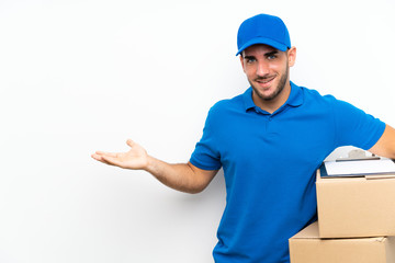 Delivery man over isolated white background holding copyspace imaginary on the palm