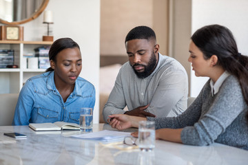 Financial planner going over documents with an African American couple - Powered by Adobe