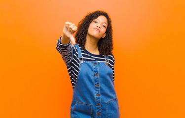 young pretty black woman feeling cross, angry, annoyed, disappointed or displeased, showing thumbs...