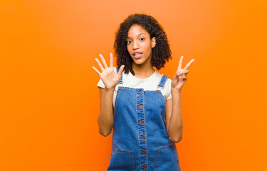 young pretty black woman smiling and looking friendly, showing number seven or seventh with hand...