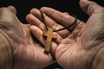 The crucifix is in the hands of a man who is praying for the blessing of his god with faith.