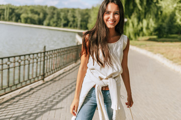 Image of beautiful young brunette woman smiling broadly with a windy blowing long hair in the park...