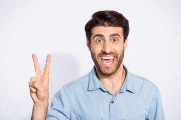 Naklejka premium Close up photo of amazing handsome guy showing v-sign symbol greets friends in good mood wear casual denim shirt isolated white color background
