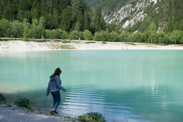 Fototapeta na wymiar A girl walks by the turquoise lake
