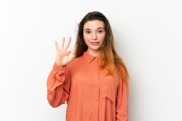 Young brunette girl over isolated white background surprised and showing ok sign
