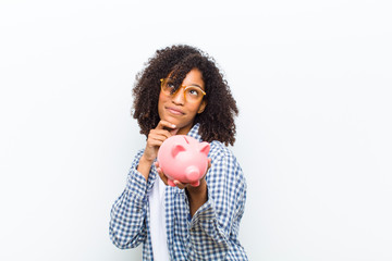young pretty black woman with a piggy bank against white wall