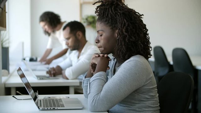 Sad young woman leaning on hands and looking at laptop. Unnerved African American woman crying at workplace. Sadness concept