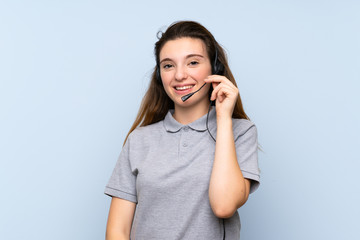 Fototapeta premium Young brunette girl over isolated blue background working with headset