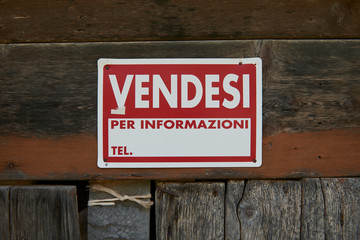 detail of a sale sign on the door of a disused old house