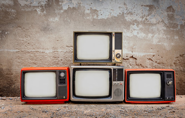 Four retro old television pile on the floor. Four old TVs placed in front of the old cement wall....