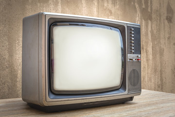 Retro old television set on wooden table with old wall background. Vintage TV filter tone.