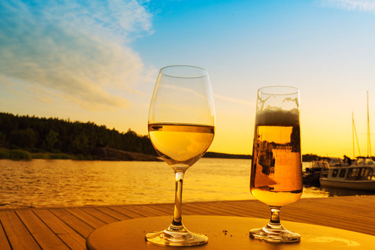 A glass of wine and beer on wooden over sea background