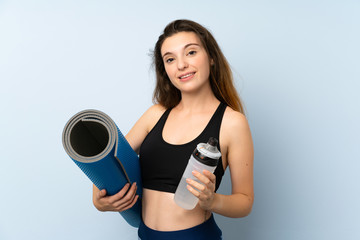 Young brunette girl with mat and a bottle of water over isolated background