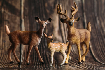 Obraz premium figure of a toy deer, DOE and fawn on a wooden background