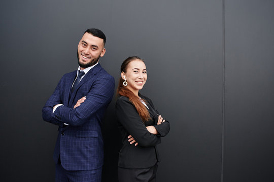 Businessman And Businesswoman Realtors On Black Office Wall Background, Asian Kazakh Entrepreneurs