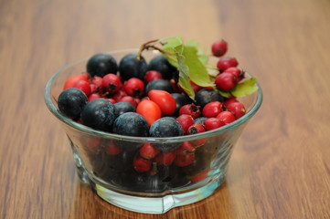 forest fruit in a glass bowl on a wooden table as decoration