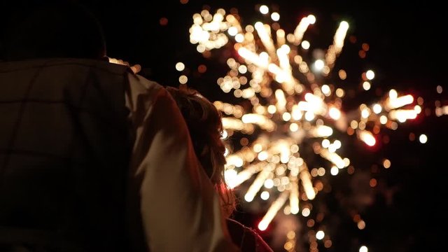 Slow motion of man and woman - a couple, look at fireworks in night sky. Close-up