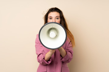 Young brunette girl with blazer over isolated background shouting through a megaphone