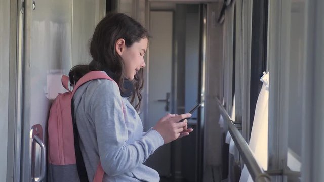 little girl walks on a train compartment car with a backpack and a smartphone. travel transportation railroad concept. the girl in the train at the window corresponds lifestyle the girl in the train