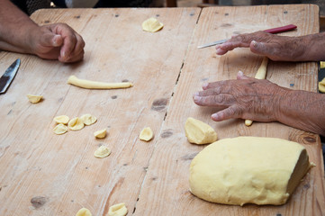 Knead the homemade orecchiette baresi. Typical fresh pasta from Bari, Puglia region, Italy. Working hands. Hands of an old woman. Italian small business owners. Ancient tradition.